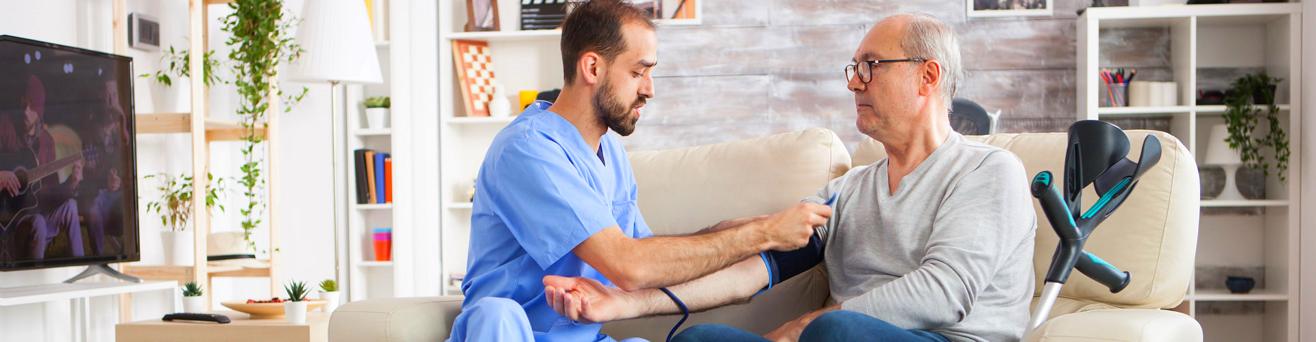 caregiver taking blood pressure level of elderly man