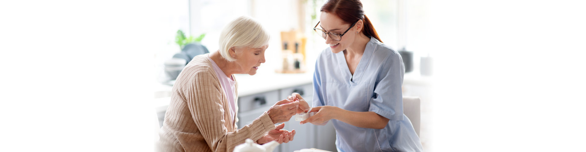 Caregiver wearing glasses and uniform giving vitamins to senior woman