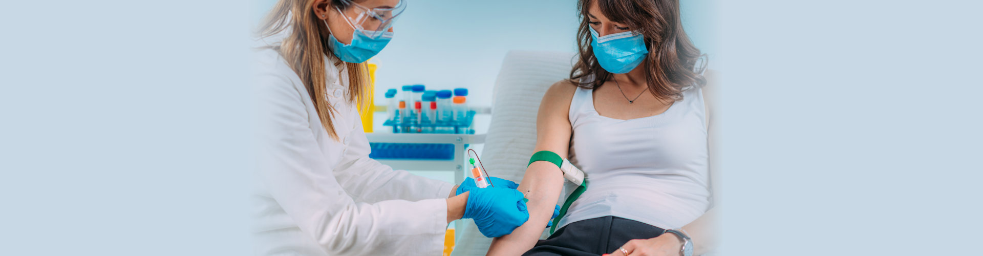 Medical worker with PPE taking blood sample from patient in a hospital