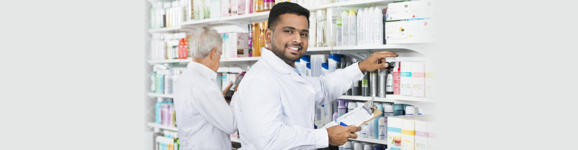 Smiling Chemist Counting Stock With Colleague In Pharmacy