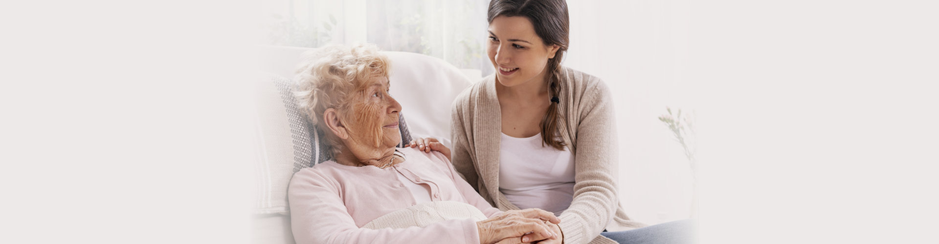 caregiver attending to elderly woman lying on bed